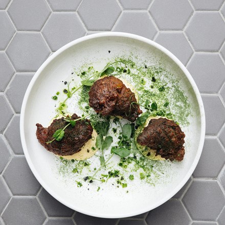 Top view of a food dish on a white plate includes lamb meatballs, spiced yoghurt, gremolata, dukkah.
